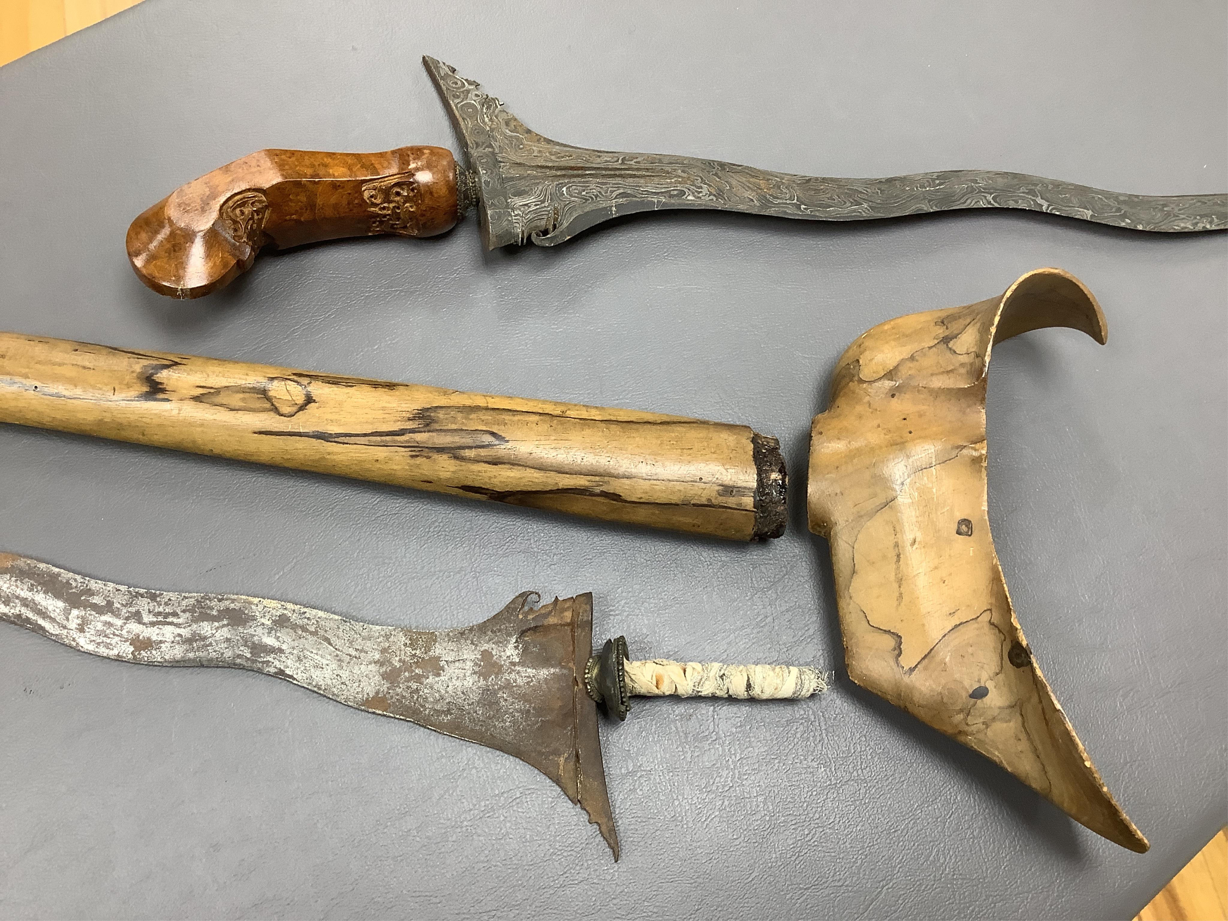 Eighteen assorted world weapons comprising a silver jambya (pommel missing), a knobkerry, a dha, two kris (one with handle missing), a lohar, three kukris, a djambok, a Chinese trousse, a chora, a flyssa, five others and